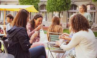Eine Gruppe Frauen sitzt an einem Tisch im Innenhof des Berner Generationenhaus.