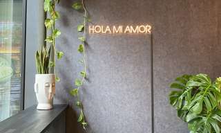 An einer grauen Wand hängt in Leuchtschrift "Hola mi amor"