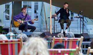 James Gruntz singt auf der Bühne des Berner Generationenhaus, das Publikum hat in Liegestühlen Platz genommen.