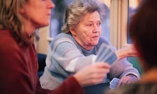 Eine jüngere und eine ältere Frau an einem Tisch mit Spielkarten in den Händen.