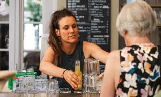 Eine Frau bedient an der Sommerbar im Innenhof des Berner Generationenhaus eine Kundin.