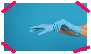 Vor einem blauen Hintergrund sind Hände in blauen Plastikhandschuhen zu sehen.