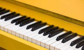 Blick auf die Tastatur eines knallgelben Klaviers.