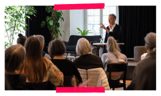 Eine Person steht auf einer Bühne und spricht zum Publikum.