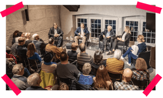 Vier Personen sitzen auf einer Bühne vor Publikum.