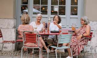 Vier Frauen sitzen an einem Tisch im Innenhof und führen ein angeregtes Gespräch.