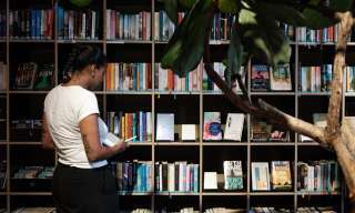 Person steht vor einen grossen Bücherregal und liest ein Buch
